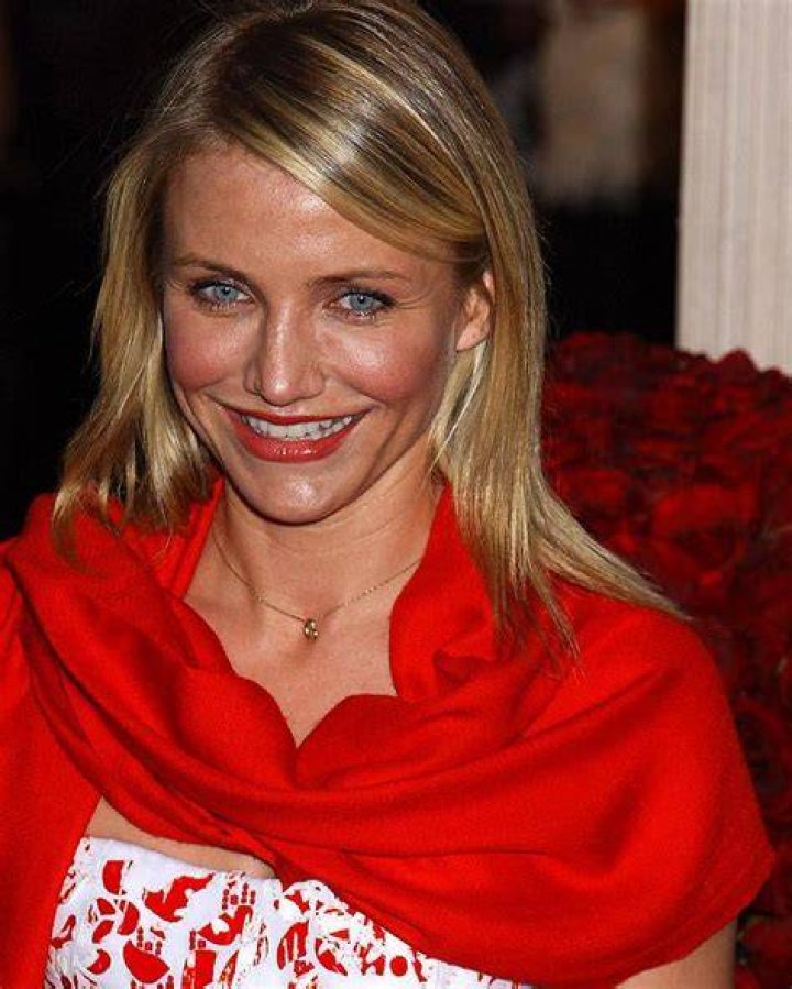 Cameron Diaz smiling in front of a white, red, and black background
