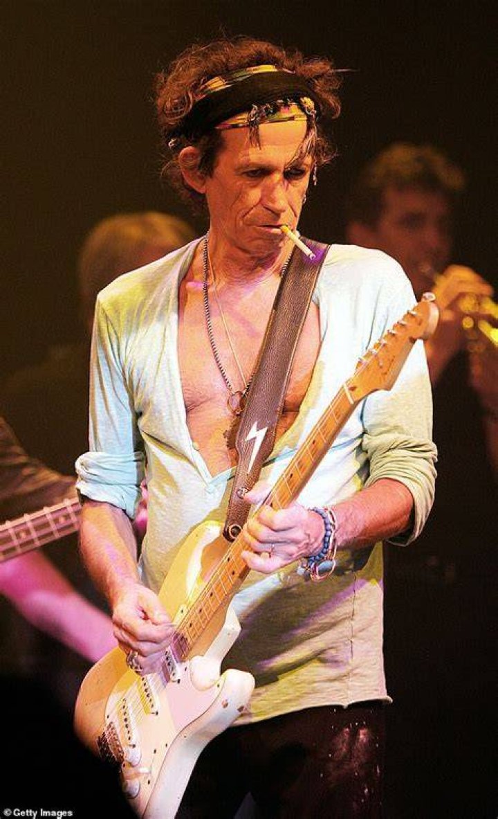 Keith Richards smoking on stage while playing guitar, looking down