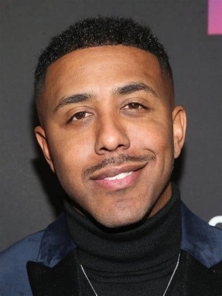 Marques Houston smiling in front of a black wall