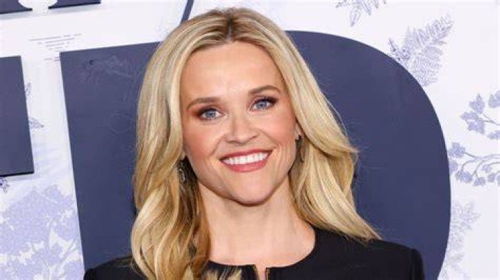 Reese Witherspoon smiling in front of a white background